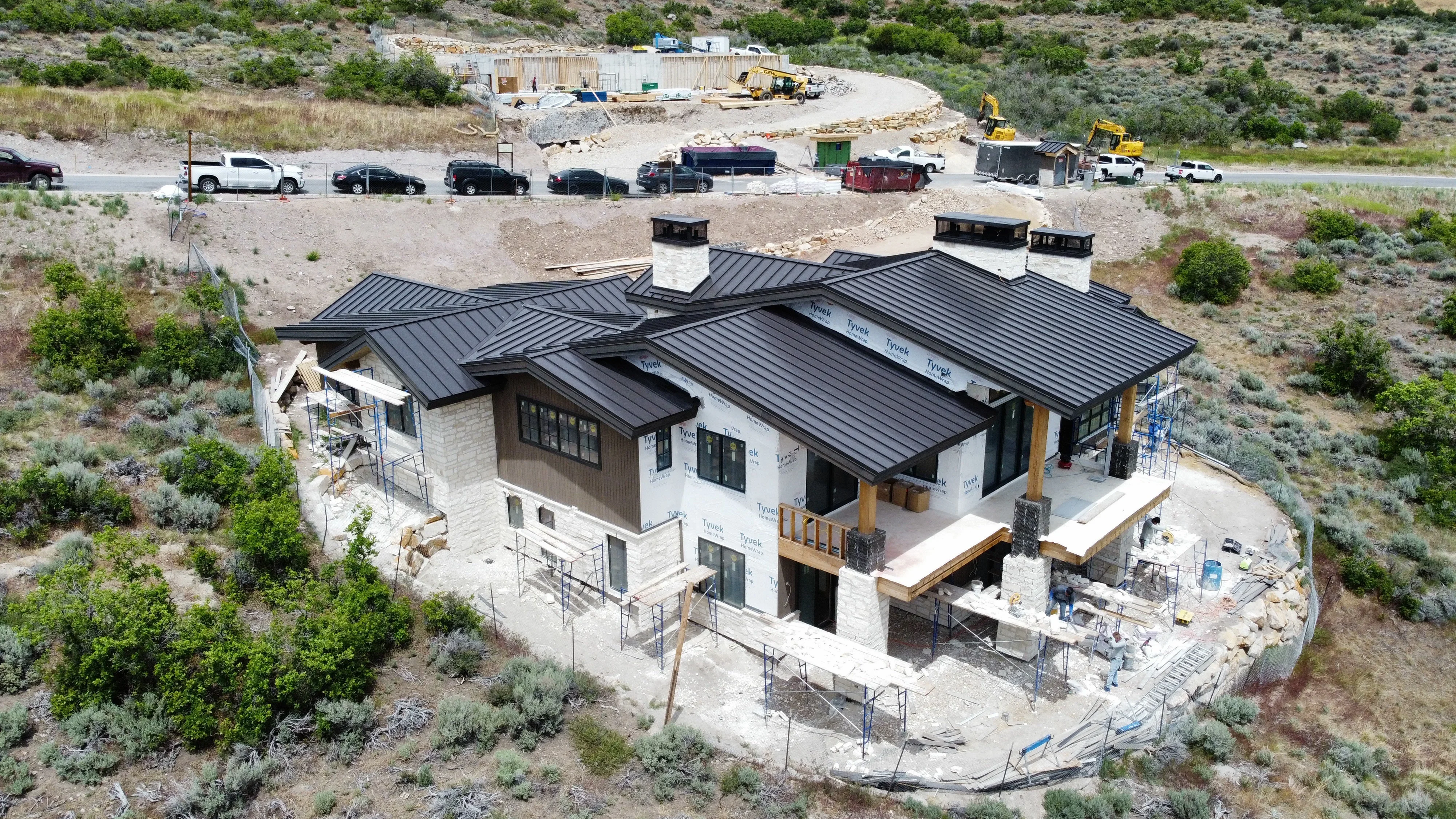 Standing seam metal roof on modern home with stone foundation and multiple roof planes under construction