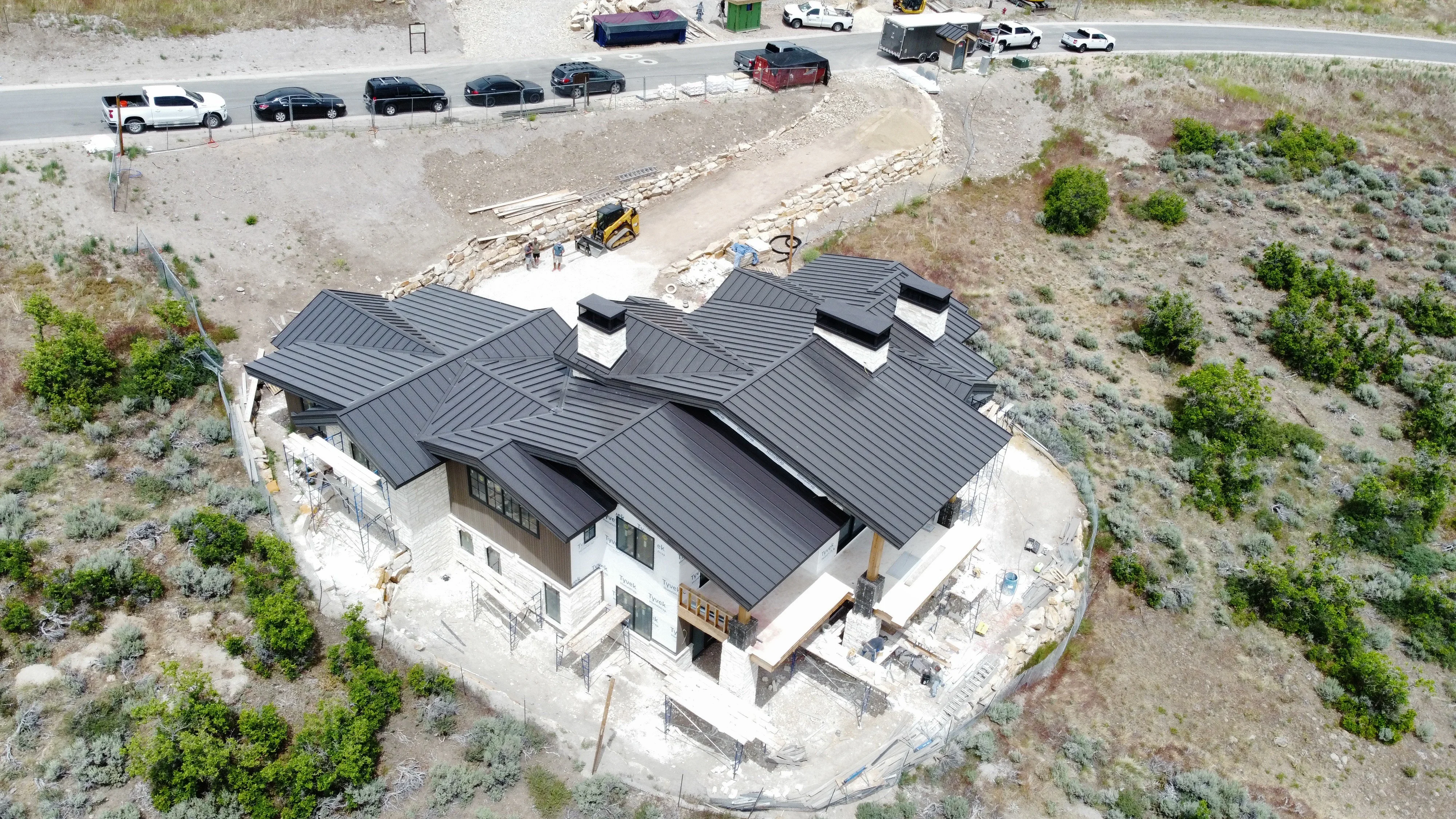 Aerial view of standing seam metal roof installation on white residential home with multiple roof planes