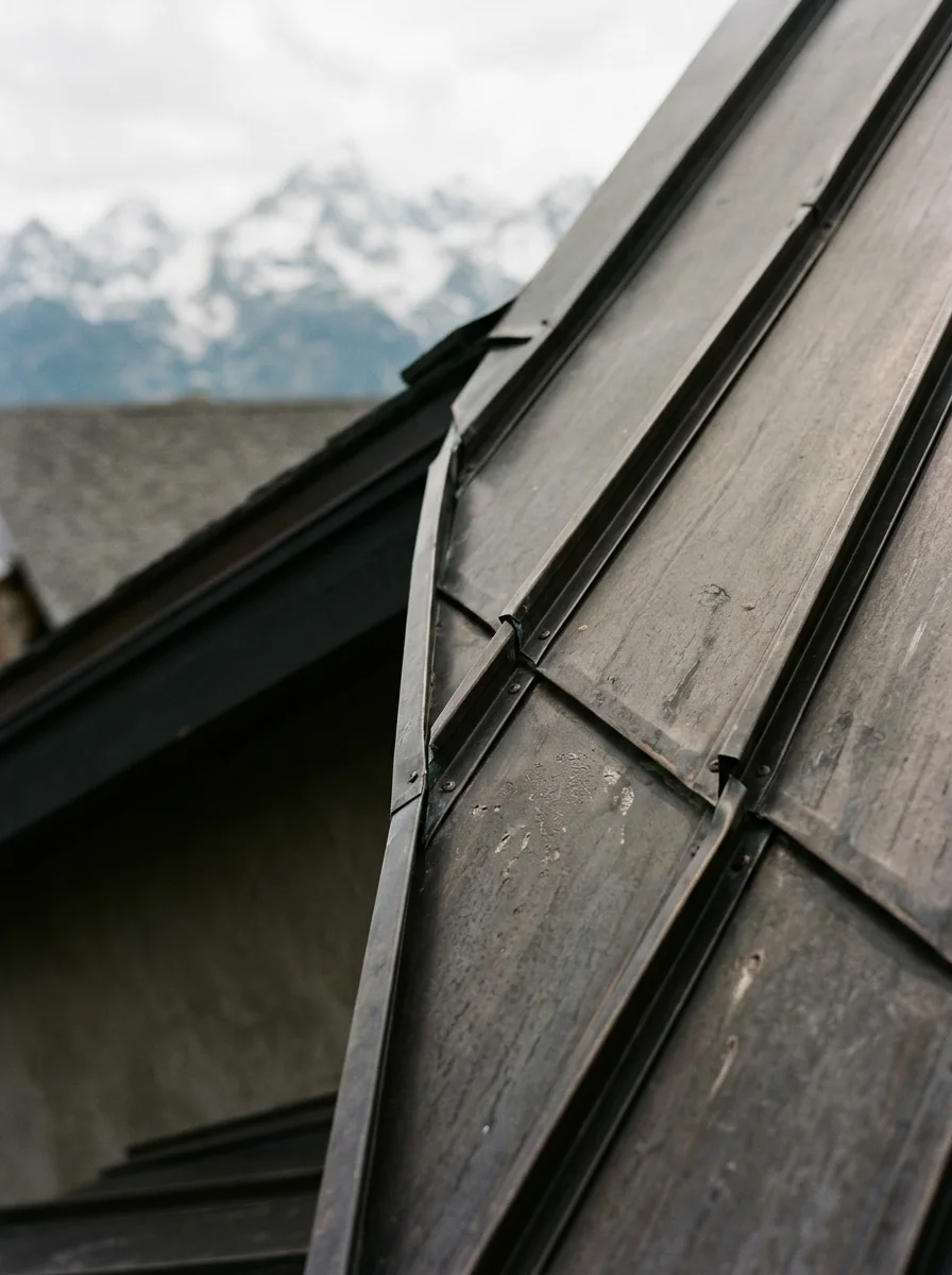 Close-up of standing seam metal roofing panels installed on a steep-pitch Wasatch Back home, showing the raised interlocking seam detail.